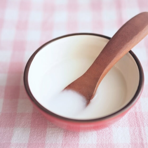 木のスプーンとピンクのボウルに入ったお粥