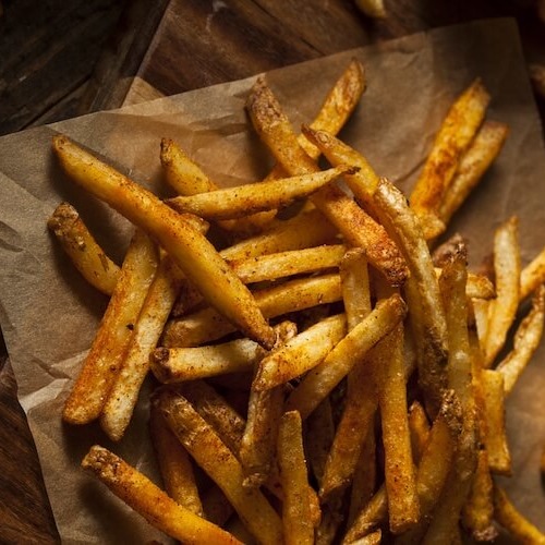 オーブンペーパーの上に出汁パウダーがまぶされたフライドポテトが盛られている